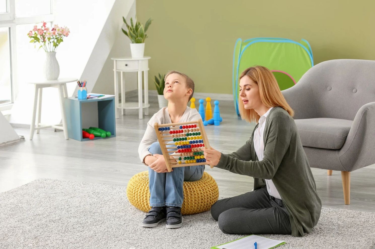 répit TSA à propos répit tsa à propos : une femme joue avec un enfant et un boulier sur la moquette